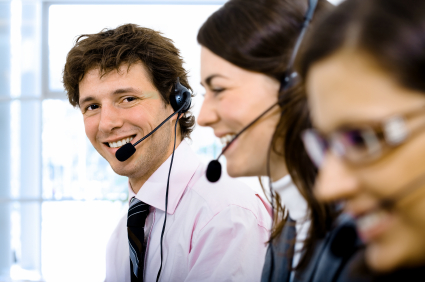 Customer service team working in headsets. Focus placed on smiling man in back.
